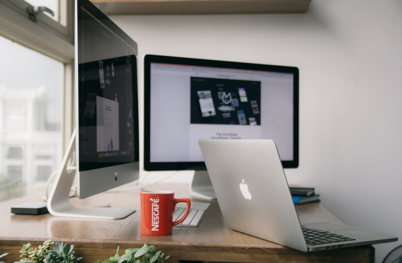 A bright, modern office setup with computers and a mug on a desk.